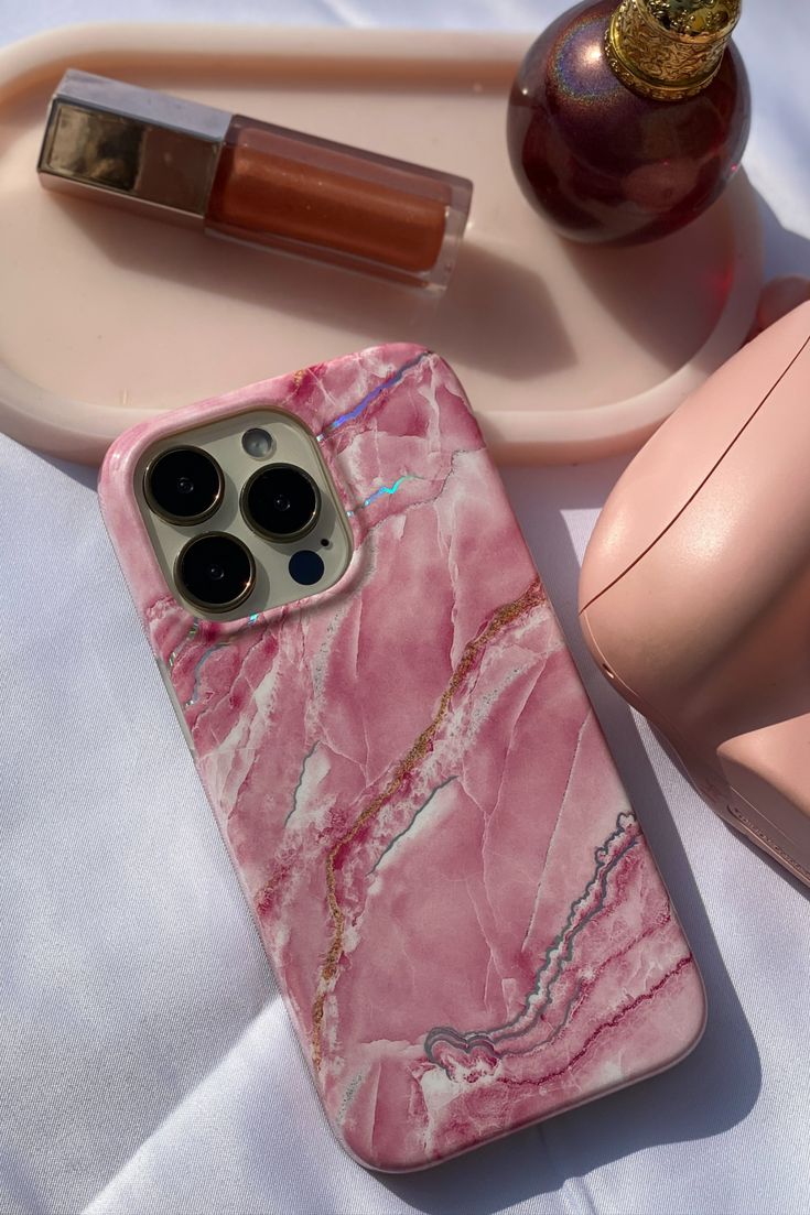 a pink marble iphone case sitting on top of a table next to an egg and lipstick