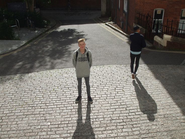 two people are walking down the street in front of some buildings and one is looking at the camera