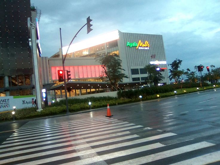 an empty street in front of a building with a neon sign on the side of it