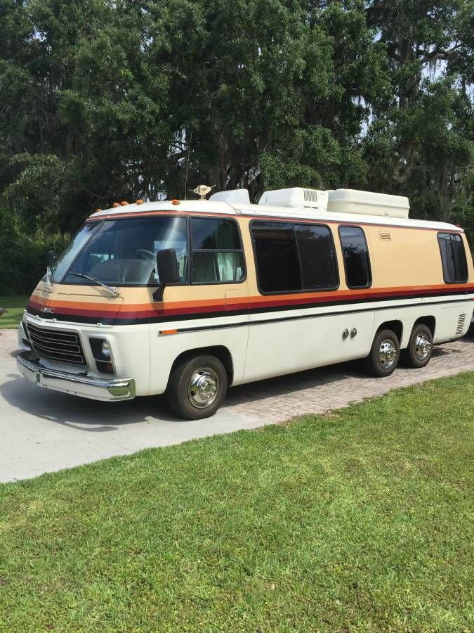 an old bus is parked on the side of the road in front of some trees