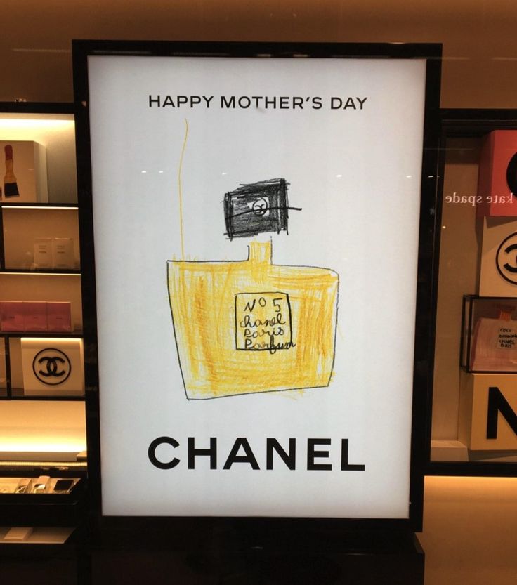 a chanel advertisement is displayed in front of a store window with the words happy mother's day written on it