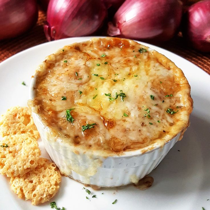 a white plate topped with food next to onion and crackers on top of a table