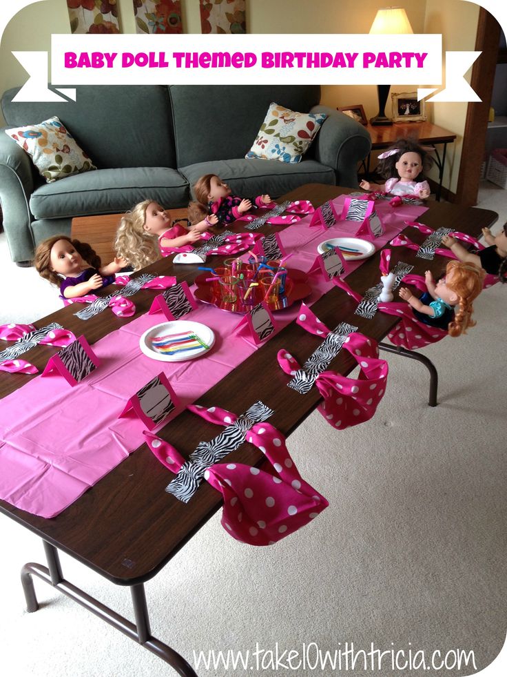 there are many dolls sitting at the table for a baby doll birthday party with pink napkins on it