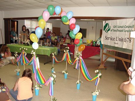 a group of people sitting in a room with balloons and streamers on the floor