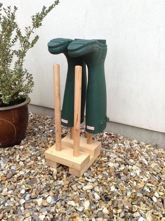 two wooden boots are on display in front of a white wall and some gravel next to a potted plant