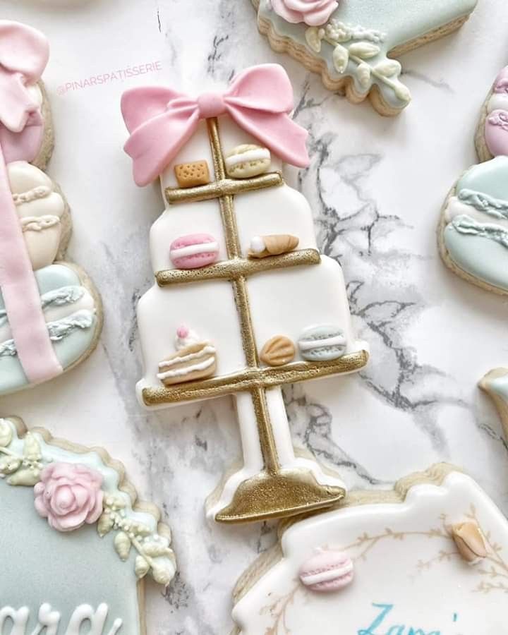 decorated cookies are arranged on a marble surface with pink bows and ribbons around the edges