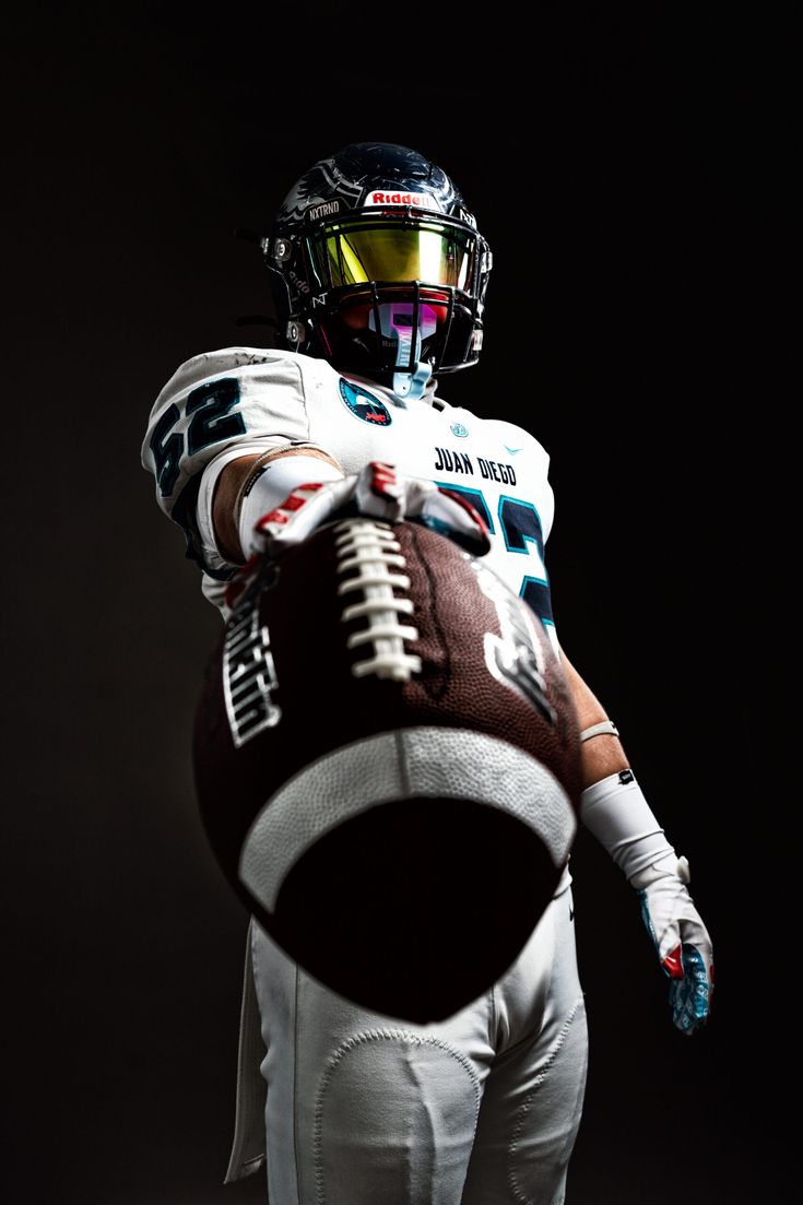 a football player wearing a helmet and holding a ball in one hand with both hands