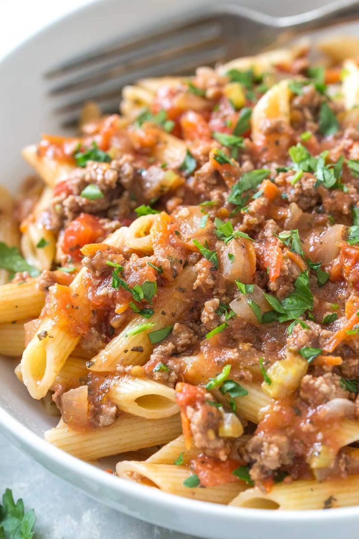 a bowl full of pasta with meat sauce and parsley on the side text reads penne bolognaese