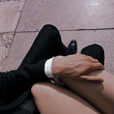 a man in a suit and tie sitting on the ground with his hand on his knee