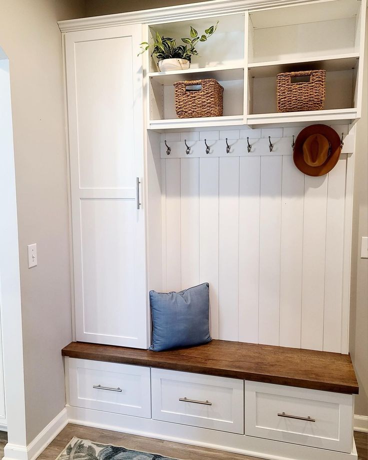 a room with some white cabinets and drawers on it's sides, including a bench