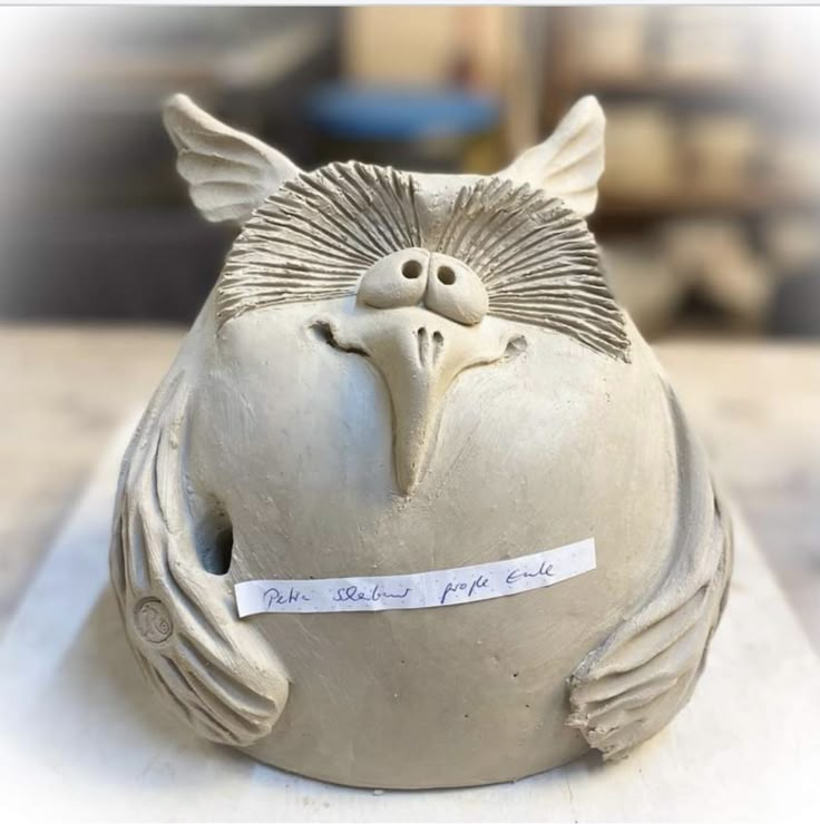 a ceramic bird sitting on top of a white table next to a piece of paper