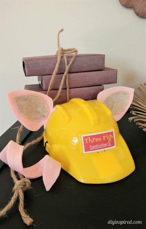 a yellow hard hat sitting on top of a table next to books and a plant