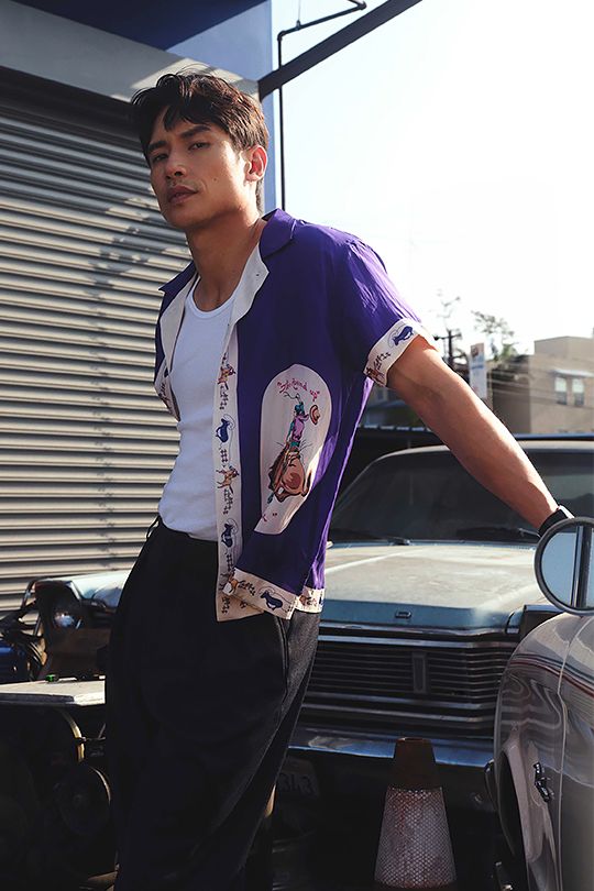 a young man standing next to a parked car