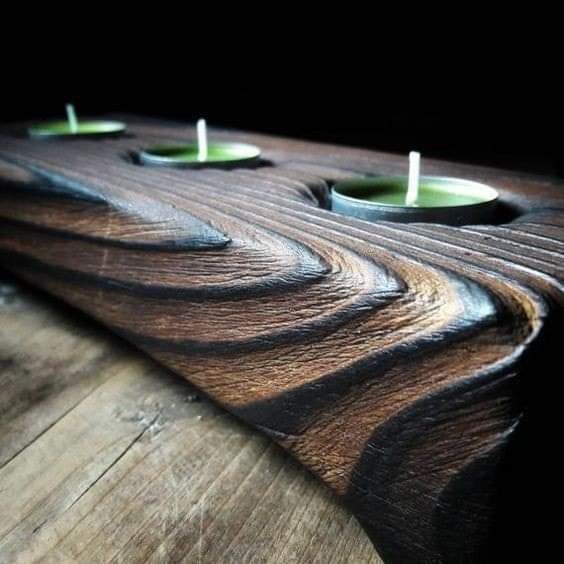 three candles are sitting on top of a wooden board with wavy lines in the center