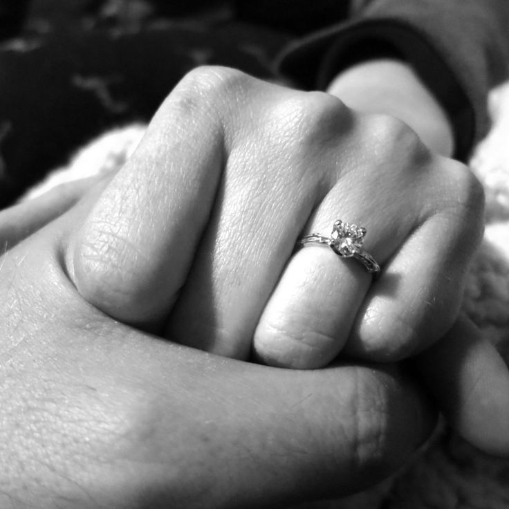 a person holding the hand of another person with a ring on their finger, in black and white