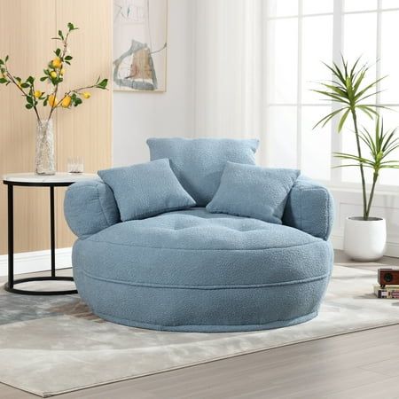 a living room filled with furniture and a large round blue chair in front of a window