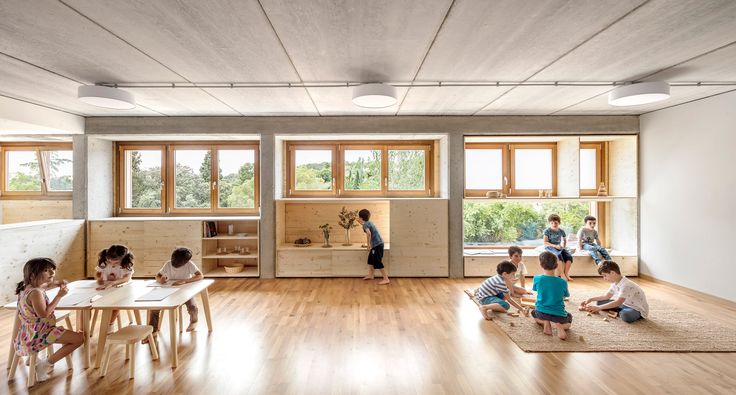 children are sitting at desks in the middle of a room with wood flooring