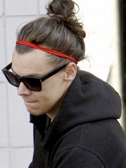 a woman wearing sunglasses and a red band around her head is looking at her cell phone