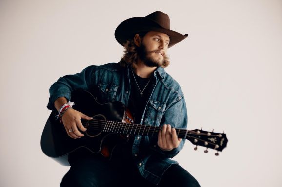 a man wearing a cowboy hat and playing an acoustic guitar