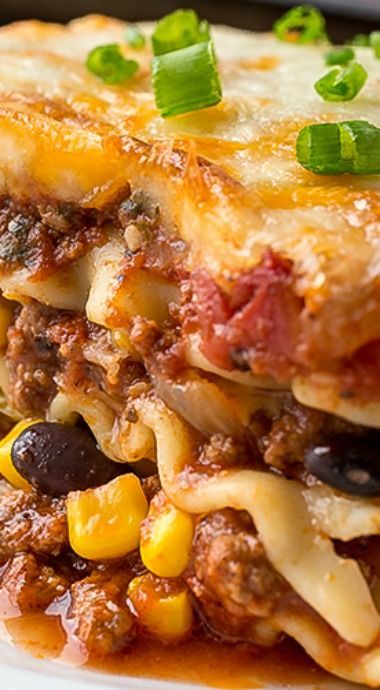 lasagna casserole with meat, cheese and black olives on a white plate