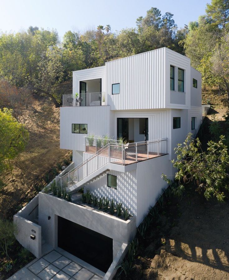 an aerial view of a modern house in the woods with stairs leading up to it