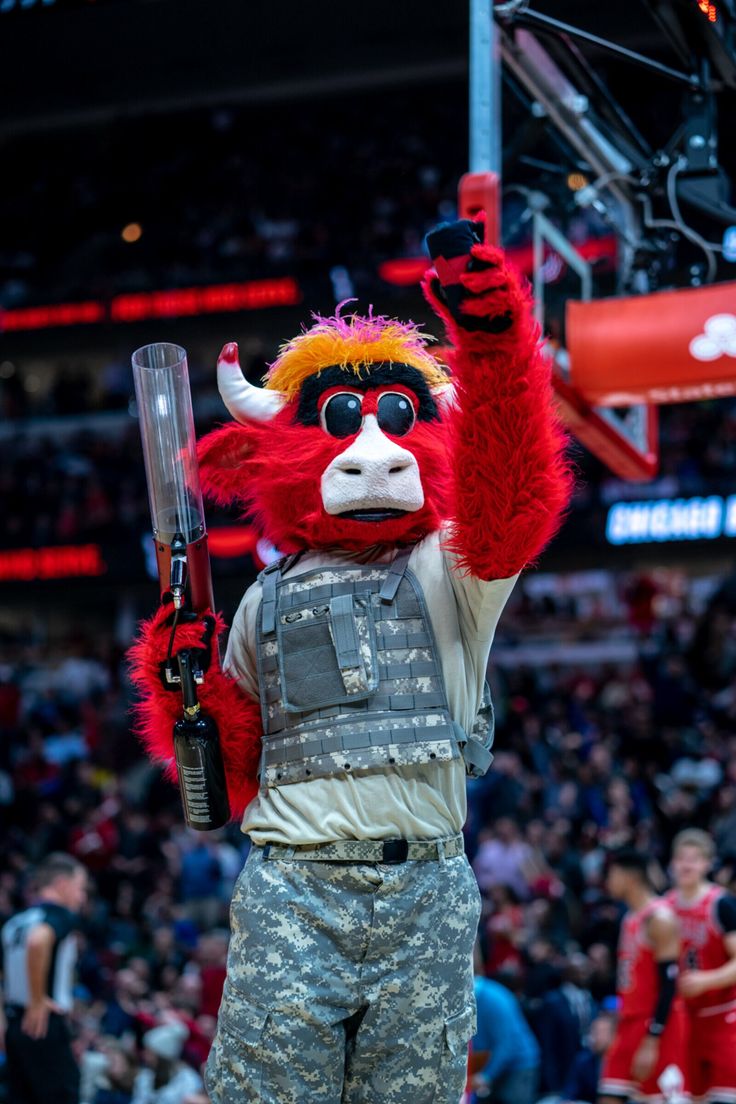 a man dressed as a red bull with a baseball bat in his hand at a basketball game