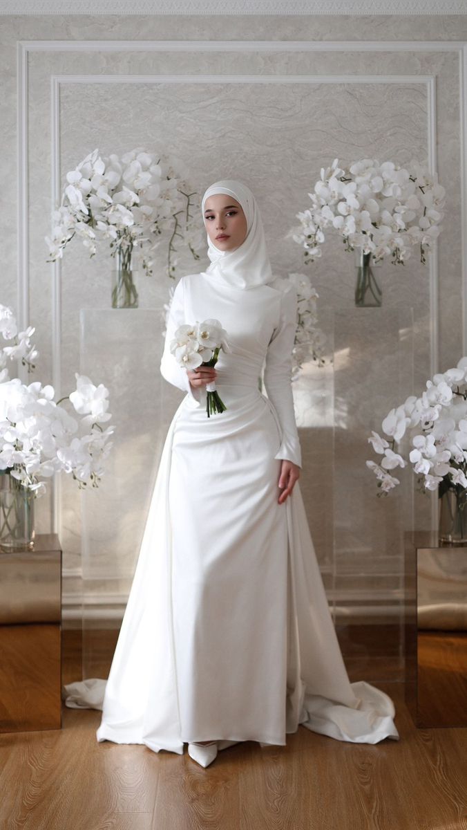 a woman in a white wedding dress standing next to vases with flowers on them