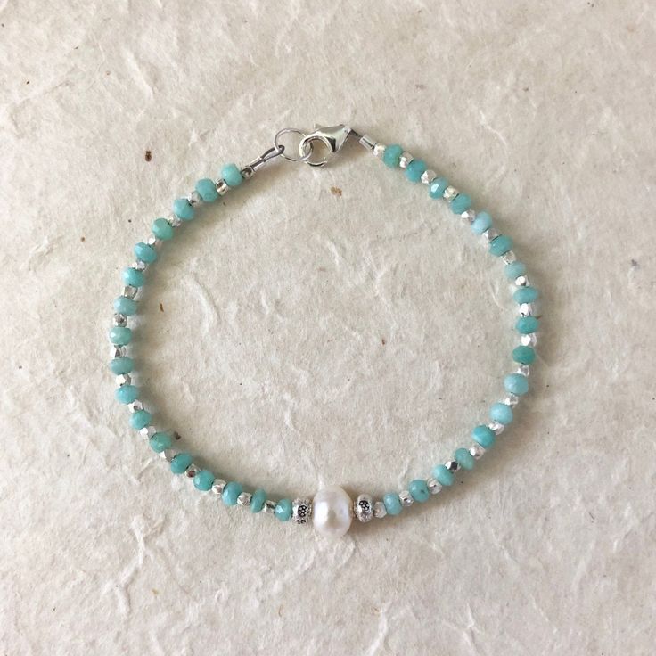 a beaded bracelet with white pearls and turquoise glass beads