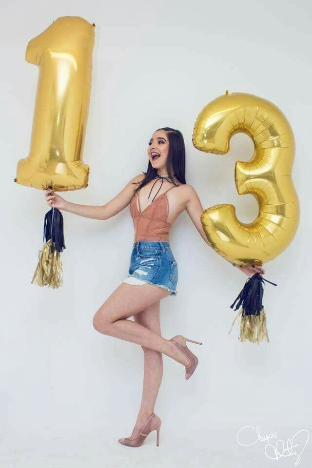 a woman holding two large gold balloons in the shape of numbers, and wearing high heels