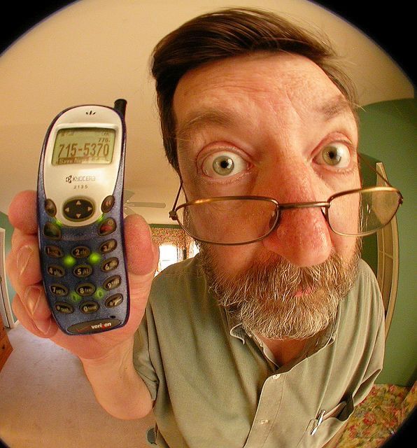 a man with glasses holding up a cell phone