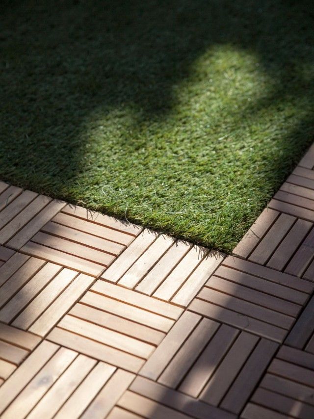 the shadow of a person's foot on grass next to a brick walkway and lawn