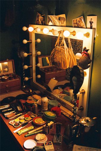 the vanity is full of makeup and other items, including a mirror with lights on it