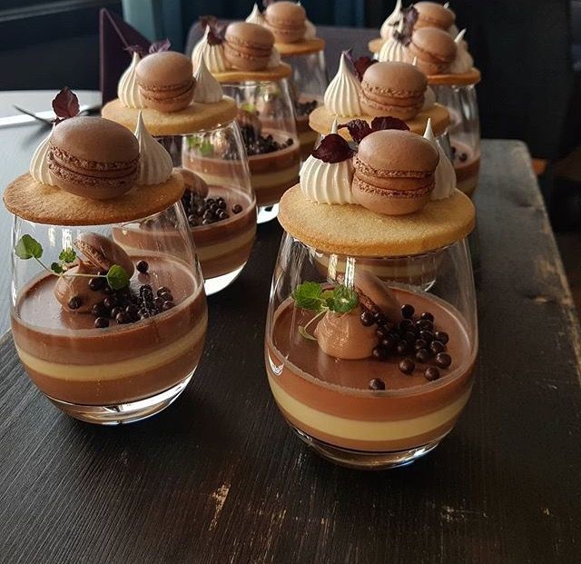 desserts are arranged in wine glasses on a table