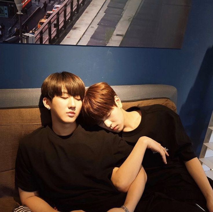 two people sitting on a couch with their arms around each other and one person holding his head