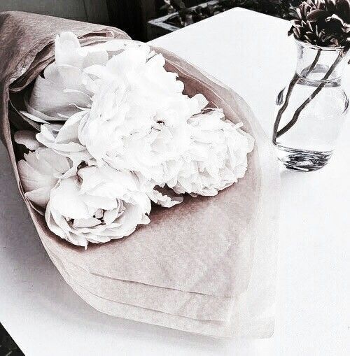 a bouquet of white flowers sitting on top of a table next to a glass vase