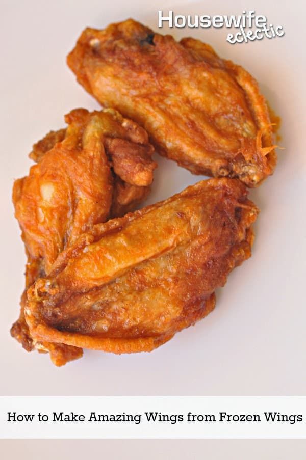 two pieces of fried chicken sitting on top of a white plate with the words how to make amazing wings from frozen wings