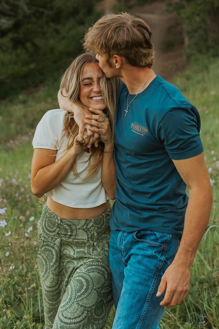 a man and woman are standing together in the grass with their arms around each other