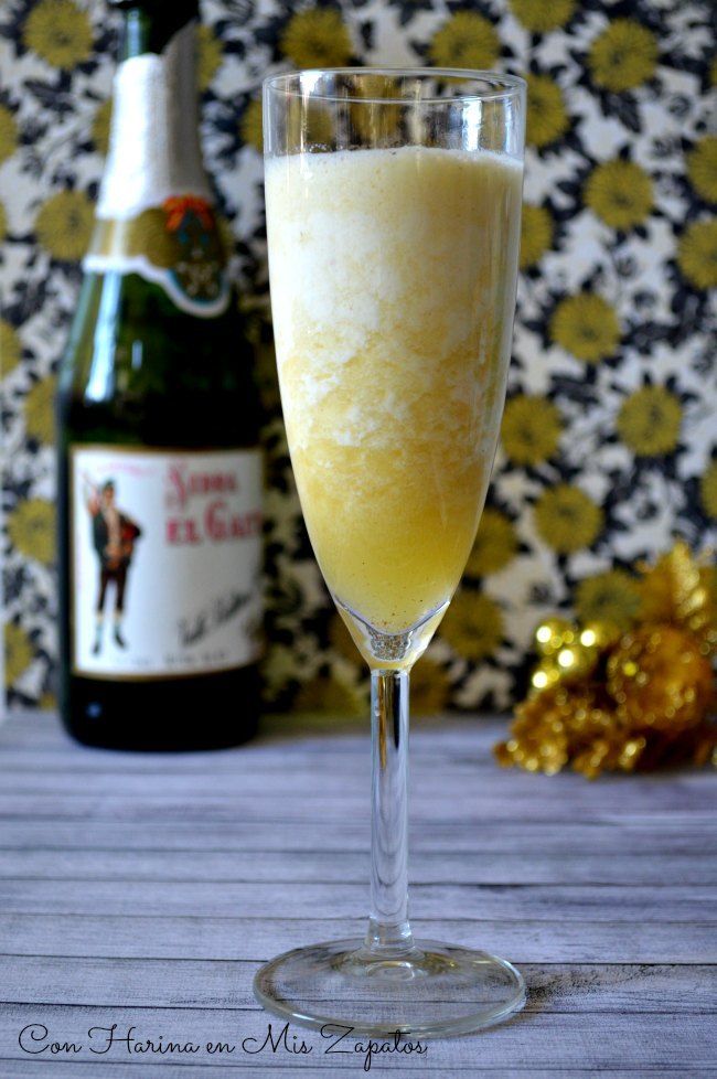 a glass filled with champagne next to a bottle of wine and some gold decorations on the table