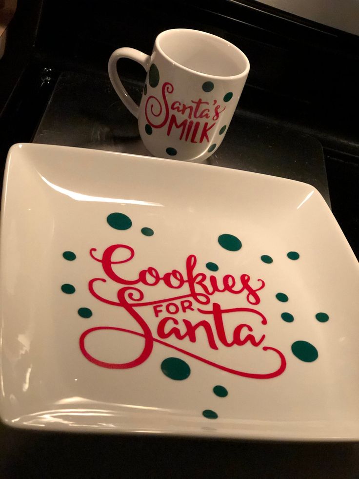 a white plate topped with a cup and saucer next to a cookie for santa mug