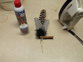 a pair of scissors, glue and feathers on the floor next to a hair dryer