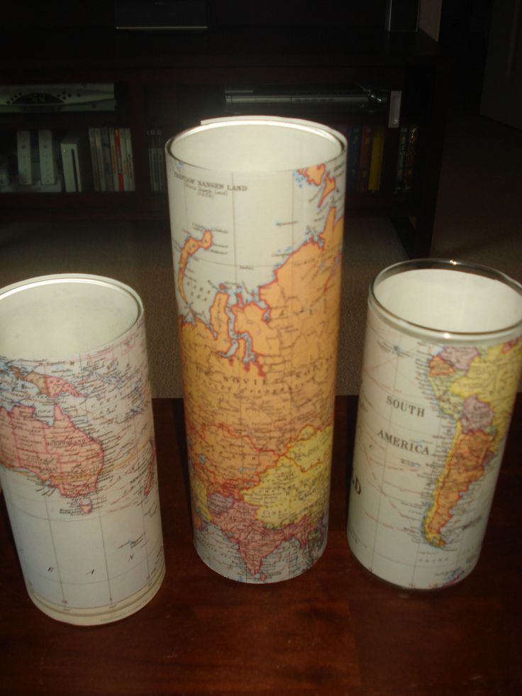 three vases with maps on them sitting on a table in front of a tv