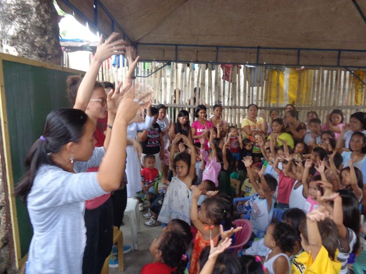 a group of people standing around each other with their hands in the air and clapping