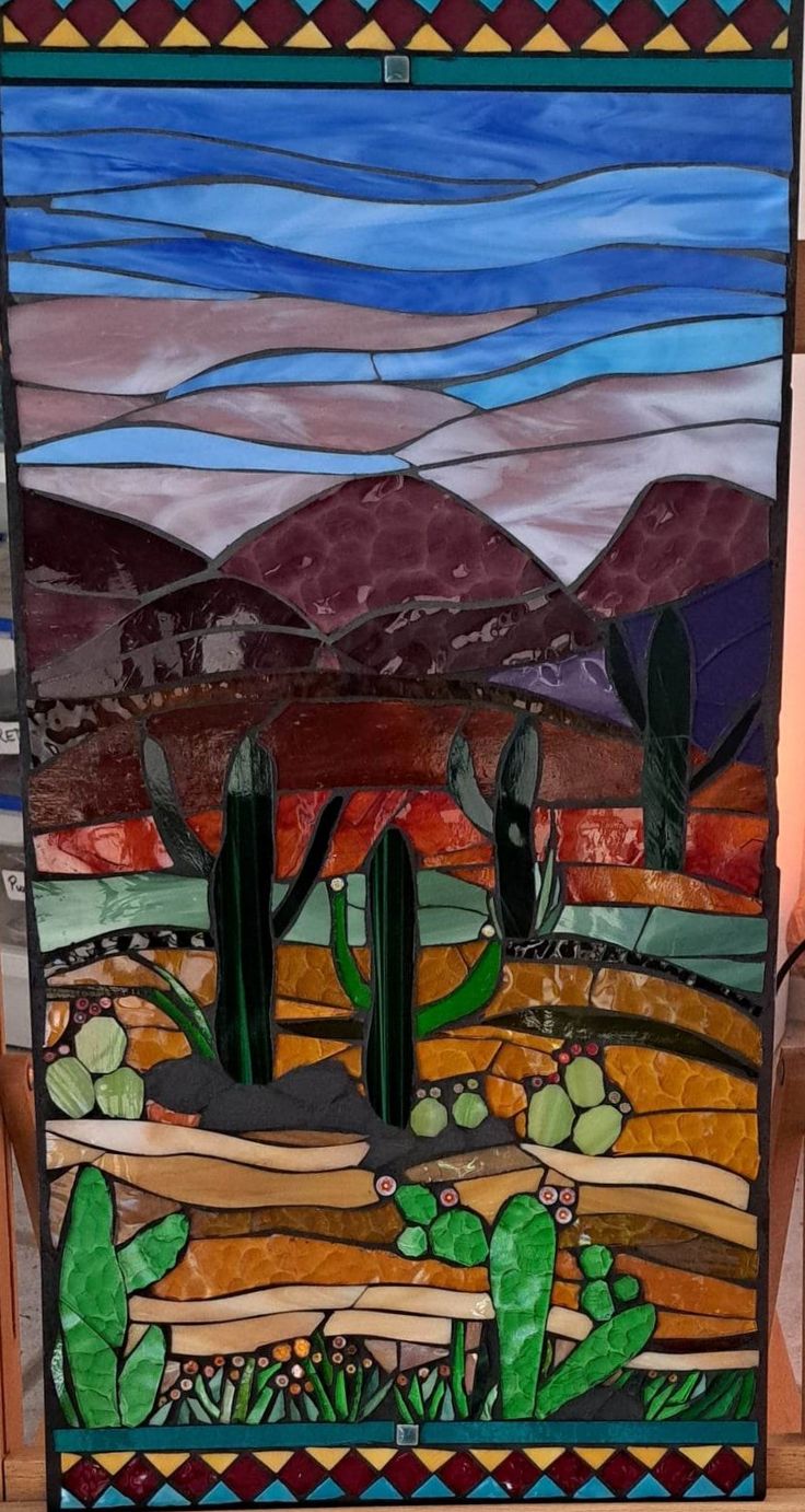 a stained glass window with cactus and mountains in the background