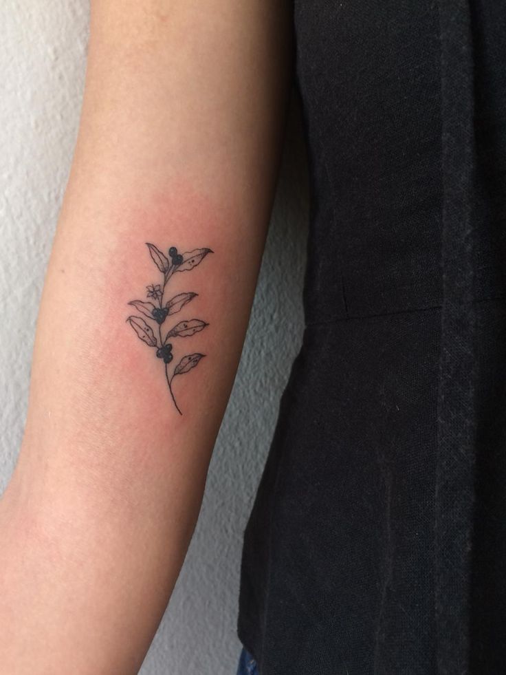 a woman's arm with a small flower tattoo on the left side of her arm