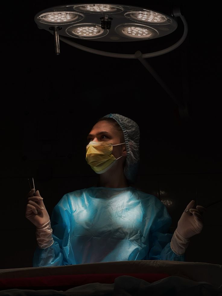 a woman in a surgical gown is holding a lit light