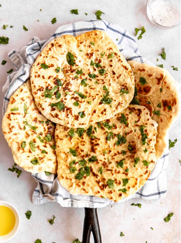 three flat breads on a plate with butter and parsley sprinkled around them