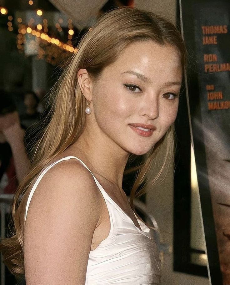 a beautiful young woman standing in front of a movie poster