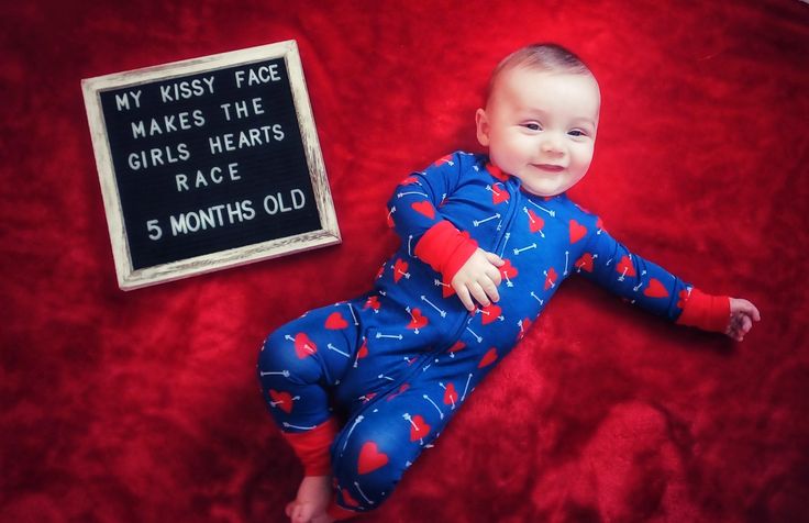 a baby laying on top of a red blanket next to a sign