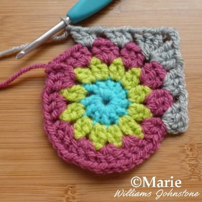 a crocheted potholder with a blue handle sits on a table next to a pair of scissors