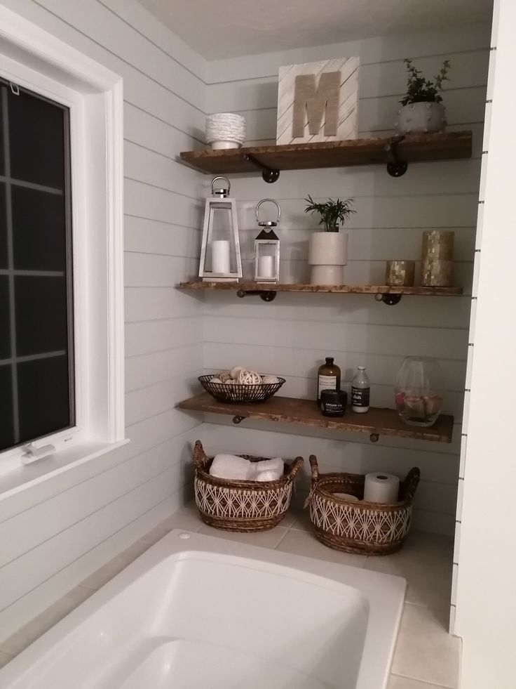 the bathroom is decorated in white and has wooden shelves with baskets on them, along with other items